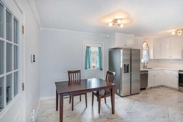 kitchen featuring a sink, white cabinets, marble finish floor, appliances with stainless steel finishes, and crown molding