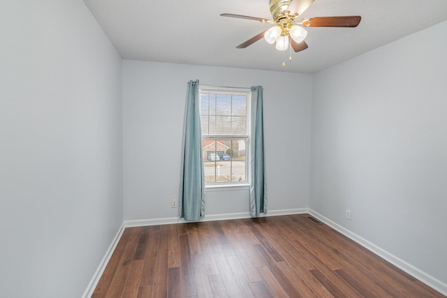 spare room with ceiling fan, dark wood-type flooring, visible vents, and baseboards