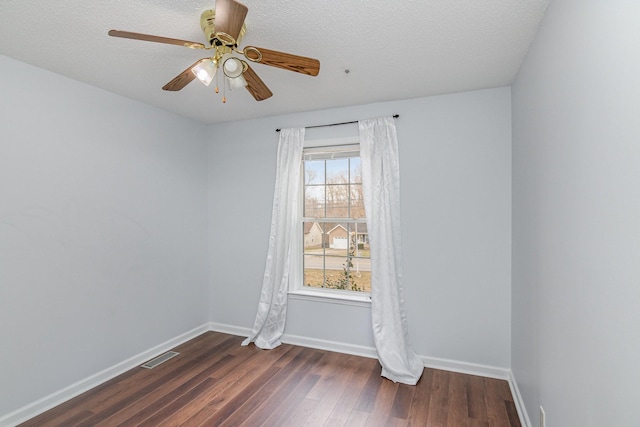 empty room featuring dark wood-style floors, ceiling fan, visible vents, and baseboards