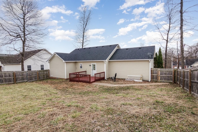 rear view of house with a deck, roof with shingles, a lawn, and a fenced backyard