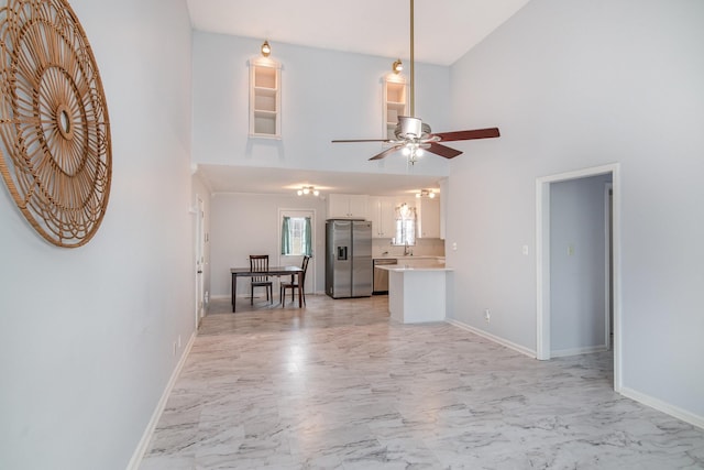 unfurnished living room featuring marble finish floor, ceiling fan, and baseboards