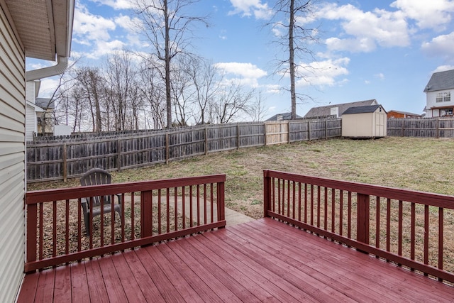 wooden deck featuring a fenced backyard, an outdoor structure, a lawn, and a shed