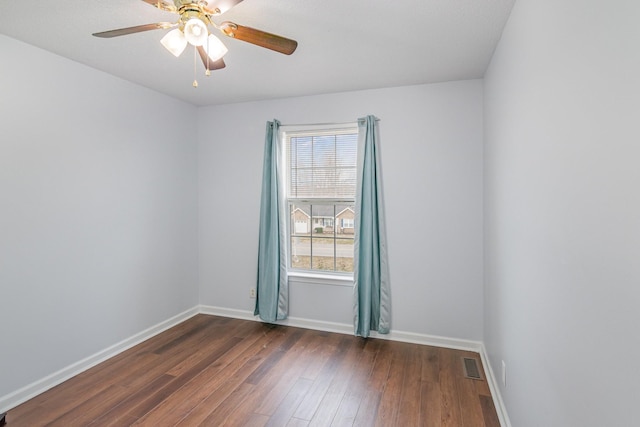 spare room with a ceiling fan, visible vents, baseboards, and dark wood-type flooring