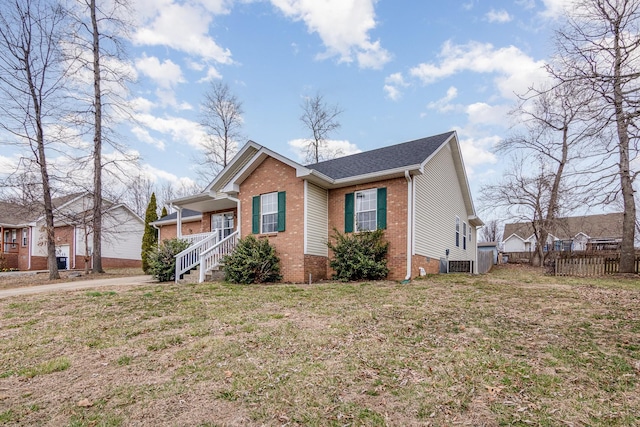 view of front of house featuring brick siding, central AC unit, a front yard, crawl space, and fence