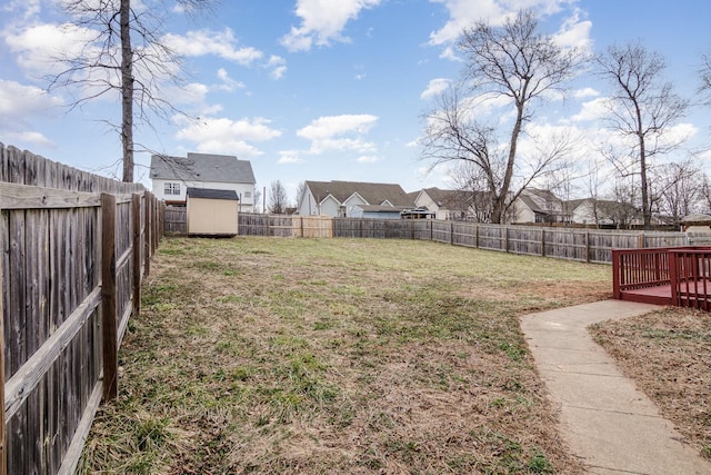 view of yard with a fenced backyard, a shed, a deck, and an outbuilding