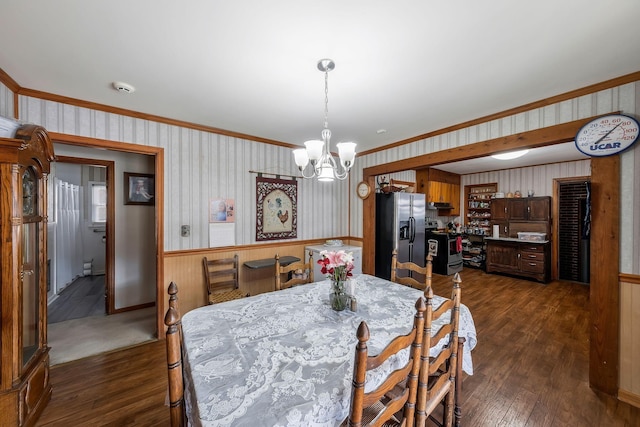 dining room featuring wallpapered walls, a notable chandelier, dark wood-type flooring, and a wainscoted wall