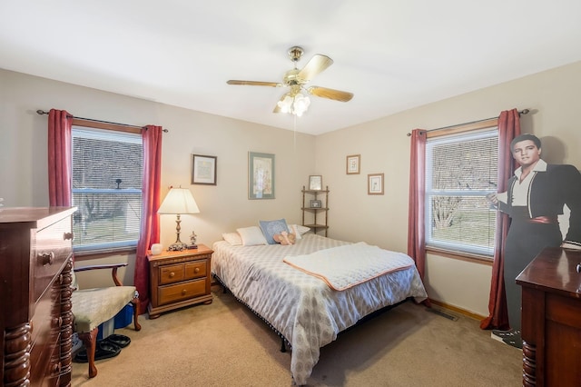 bedroom with baseboards, a ceiling fan, visible vents, and light colored carpet