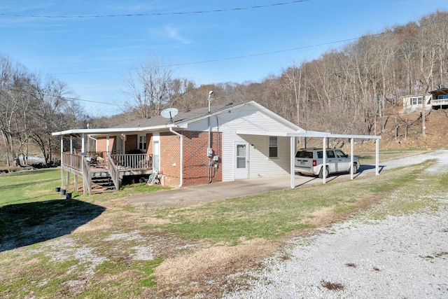 exterior space with covered porch, brick siding, driveway, a carport, and a front lawn