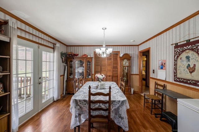 dining space featuring ornamental molding, a notable chandelier, dark wood-style floors, and wallpapered walls