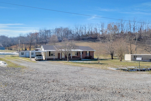 view of front of house featuring a carport, an outbuilding, covered porch, and driveway