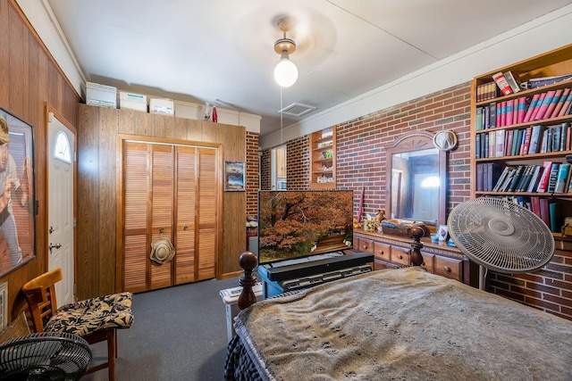 bedroom featuring a closet, visible vents, carpet flooring, wood walls, and brick wall