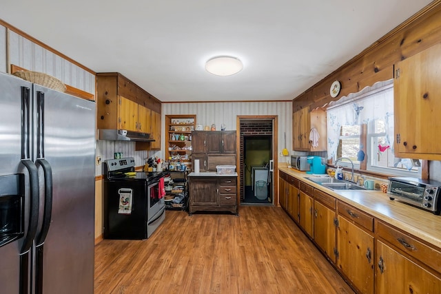 kitchen featuring brown cabinets, light countertops, appliances with stainless steel finishes, a sink, and under cabinet range hood