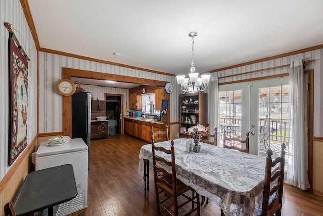 dining space featuring french doors, ornamental molding, dark wood-style floors, wallpapered walls, and an inviting chandelier