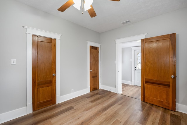 unfurnished bedroom with light wood-style floors, visible vents, baseboards, and a ceiling fan