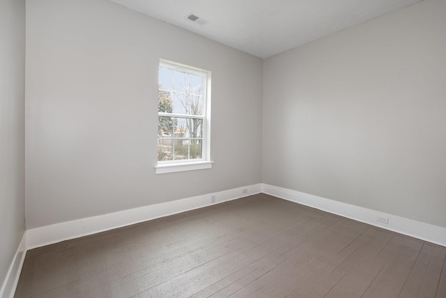 spare room featuring baseboards, visible vents, and dark wood-style flooring