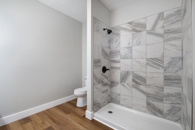 full bath featuring a stall shower, wood finished floors, toilet, and baseboards