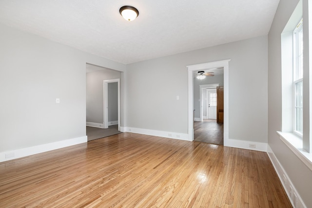 spare room with light wood-style floors, baseboards, and a textured ceiling