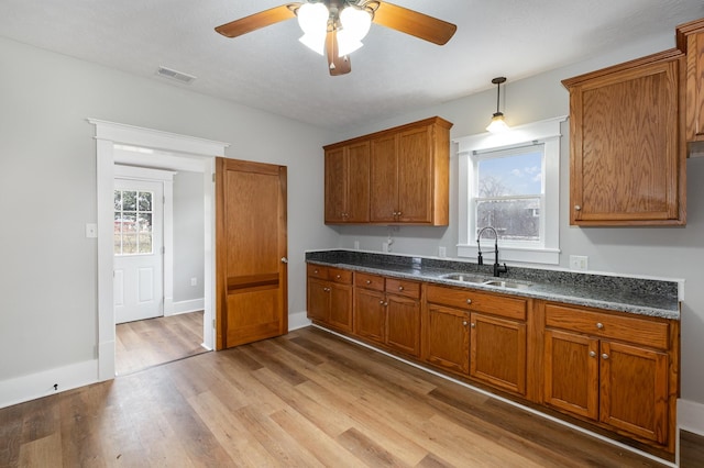 kitchen with a wealth of natural light, a sink, light wood-style flooring, and brown cabinets