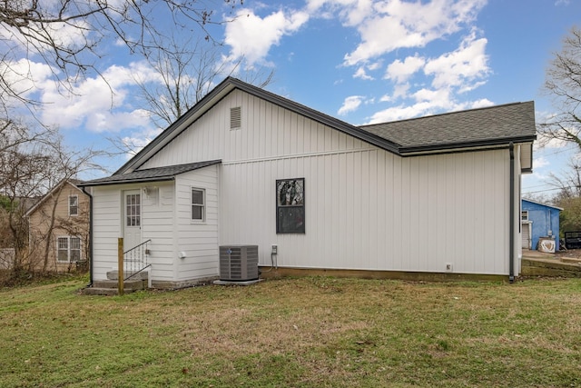 back of house featuring entry steps, central AC, a lawn, and roof with shingles