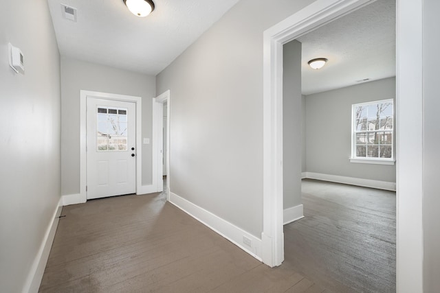 foyer with dark wood-style floors, a textured ceiling, visible vents, and baseboards