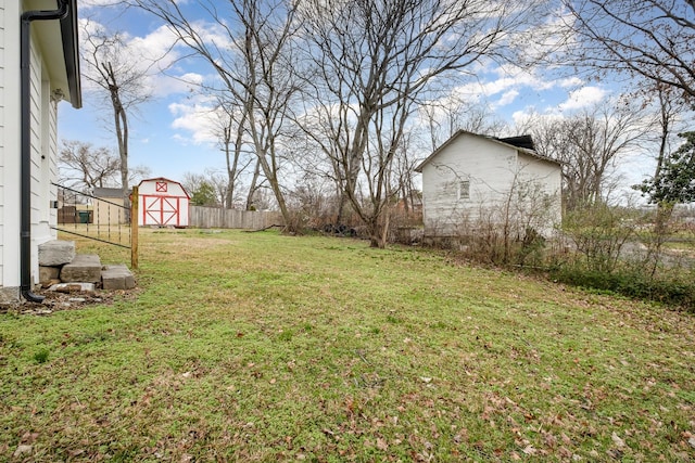 view of yard with a storage shed, an outdoor structure, and fence