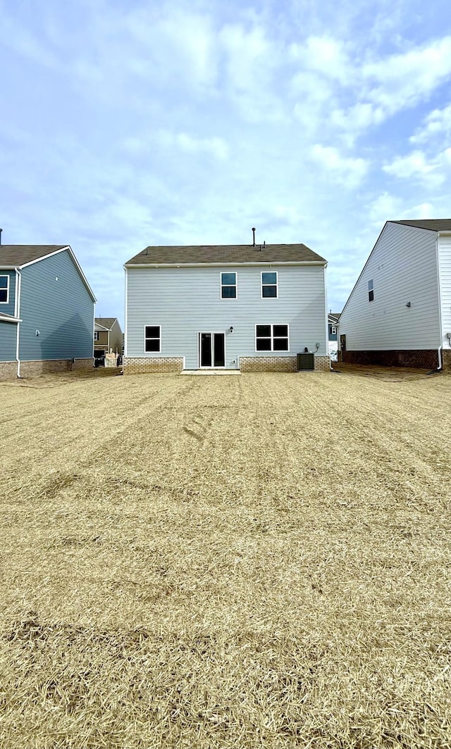 rear view of house featuring central AC and a lawn