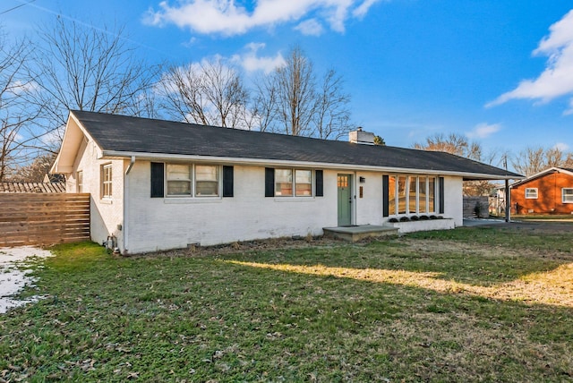 single story home with brick siding, a chimney, a front yard, and fence