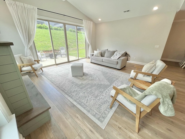 living area featuring light wood-type flooring, lofted ceiling, baseboards, and recessed lighting