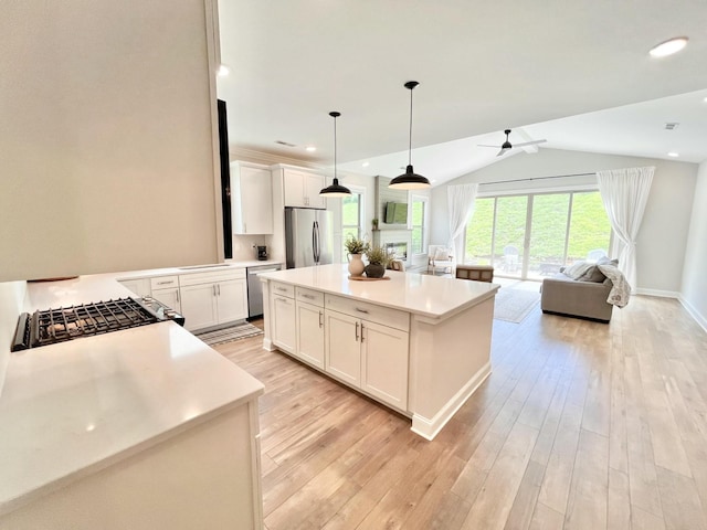 kitchen featuring white cabinetry, light countertops, appliances with stainless steel finishes, hanging light fixtures, and a center island