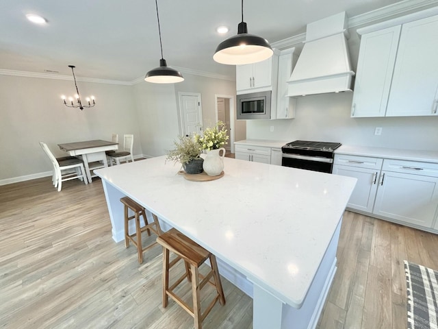 kitchen with appliances with stainless steel finishes, white cabinets, custom range hood, and hanging light fixtures