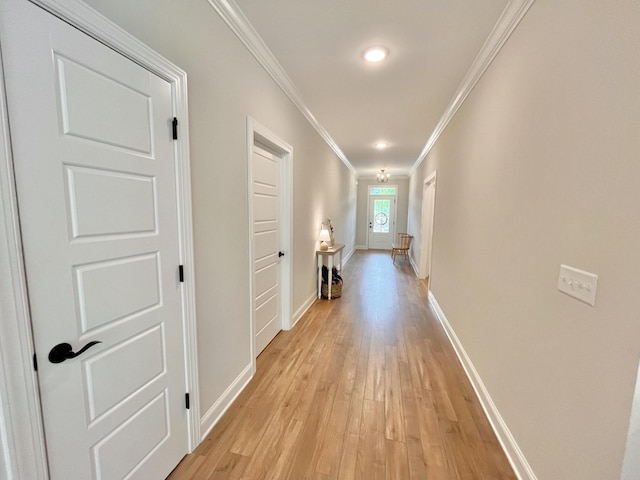 corridor featuring light wood-type flooring, baseboards, and ornamental molding