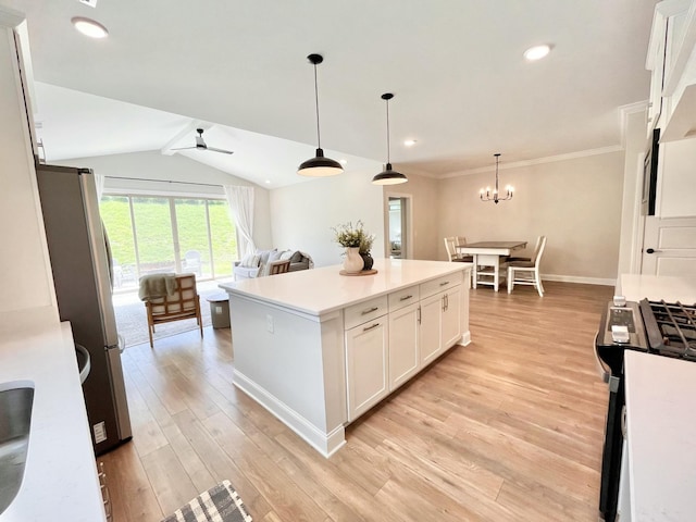 kitchen featuring a center island, decorative light fixtures, gas range oven, light countertops, and white cabinetry