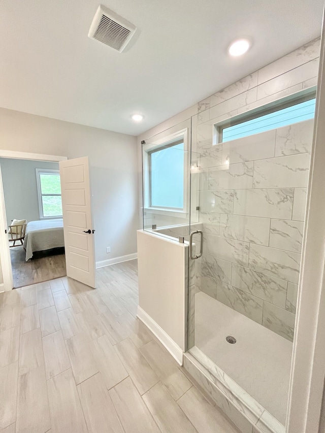 ensuite bathroom with wood finished floors, visible vents, baseboards, a stall shower, and ensuite bath