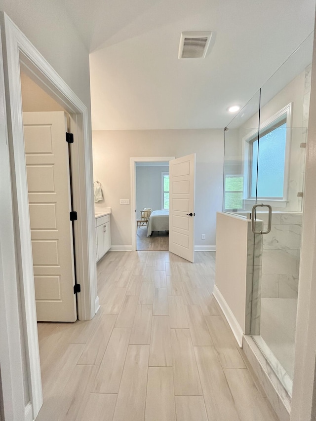 bathroom with connected bathroom, vanity, baseboards, visible vents, and a marble finish shower