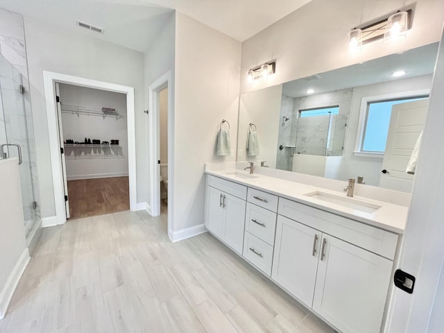 full bath with a stall shower, visible vents, a sink, and double vanity