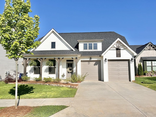 view of front of house with driveway, roof with shingles, a garage, and a front yard