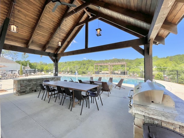 view of patio / terrace featuring a gazebo, fence, an outdoor kitchen, and a community pool