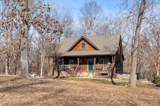 chalet / cabin featuring a porch and a shingled roof