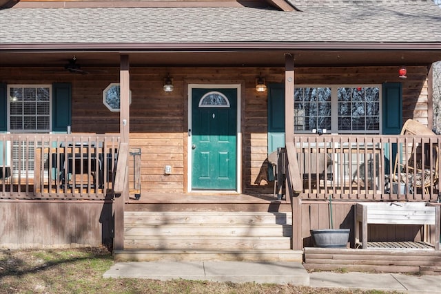 entrance to property with covered porch and a shingled roof