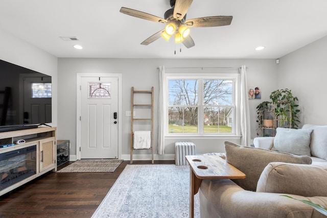 living room featuring visible vents, baseboards, radiator, dark wood-style floors, and recessed lighting