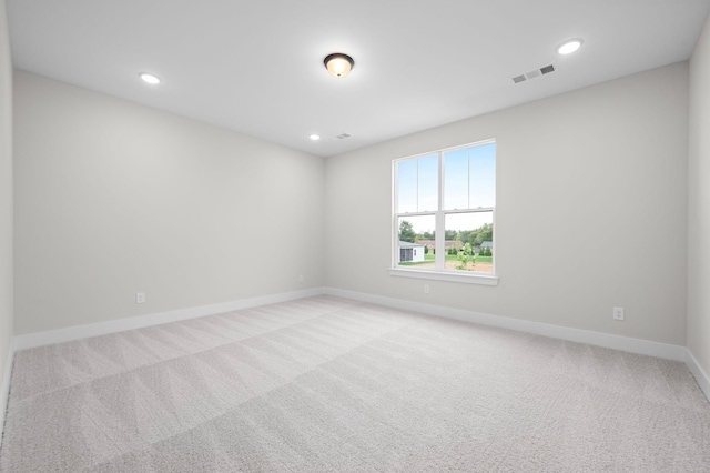 spare room with light carpet, recessed lighting, visible vents, and baseboards