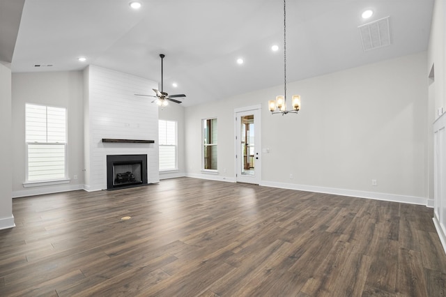 unfurnished living room featuring lofted ceiling, a large fireplace, ceiling fan with notable chandelier, dark wood-style flooring, and visible vents