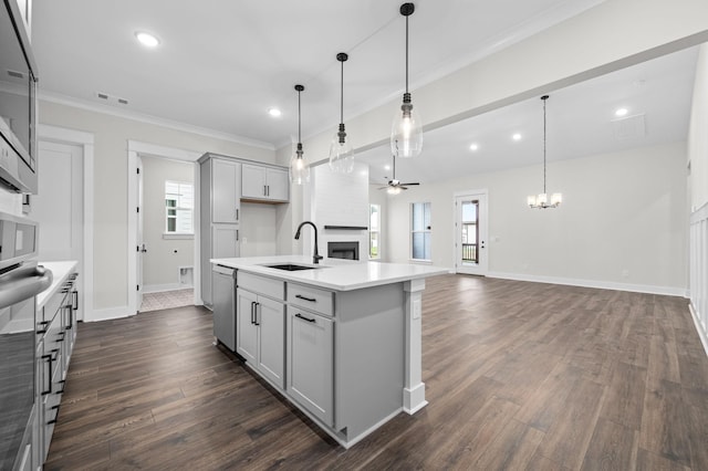 kitchen featuring decorative light fixtures, a center island with sink, light countertops, open floor plan, and a large fireplace