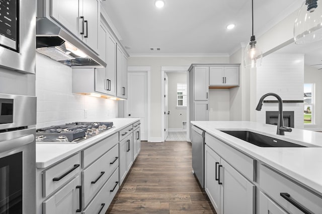 kitchen featuring appliances with stainless steel finishes, light countertops, a sink, and ornamental molding