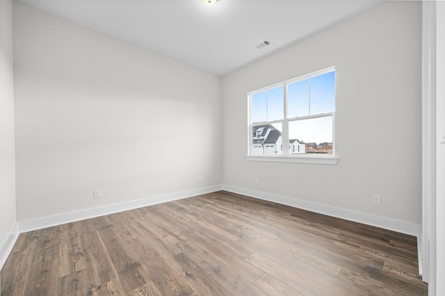 empty room featuring baseboards, visible vents, and wood finished floors