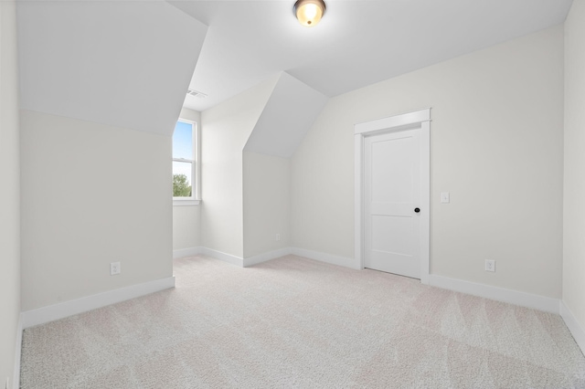 additional living space with light colored carpet, vaulted ceiling, and baseboards