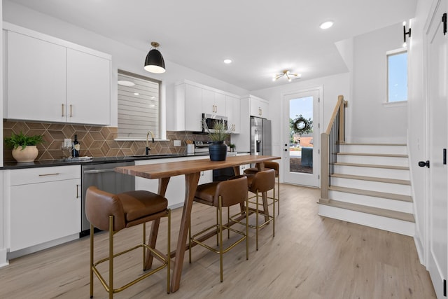 kitchen with decorative backsplash, dark countertops, stainless steel appliances, white cabinetry, and a sink