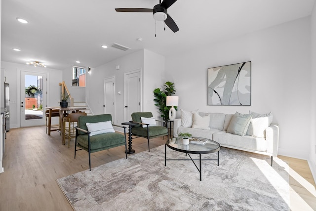 living room featuring visible vents, a ceiling fan, stairway, light wood-type flooring, and recessed lighting