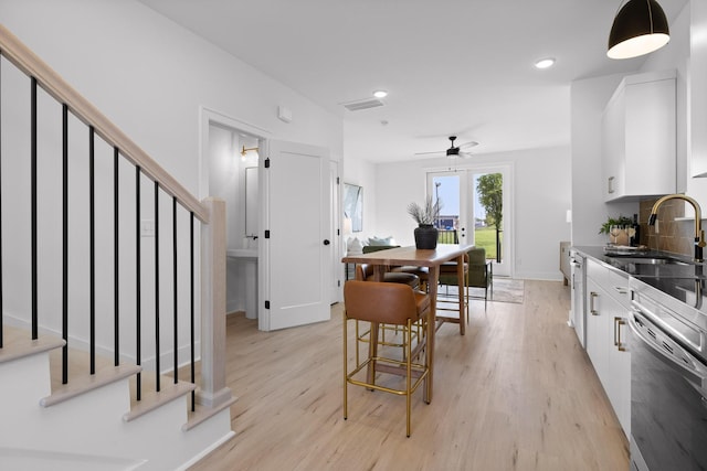 kitchen featuring dark countertops, white cabinetry, a sink, and light wood-style flooring