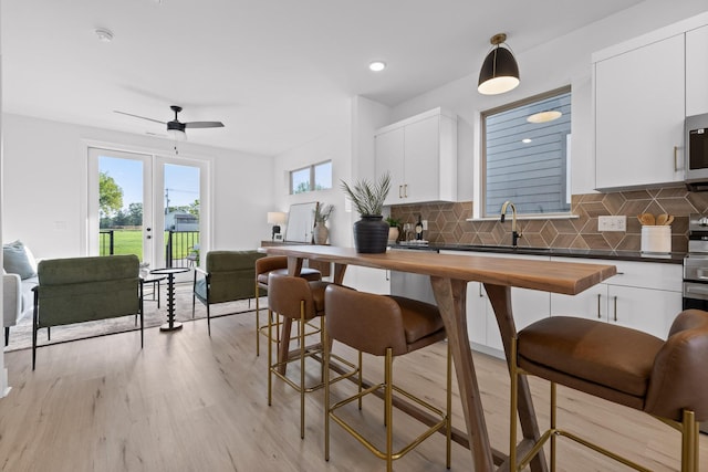 kitchen with open floor plan, butcher block counters, white cabinetry, and pendant lighting